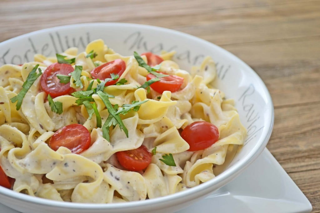 Pasta with cooking cream, cherry tomatoes, in a white bowl.