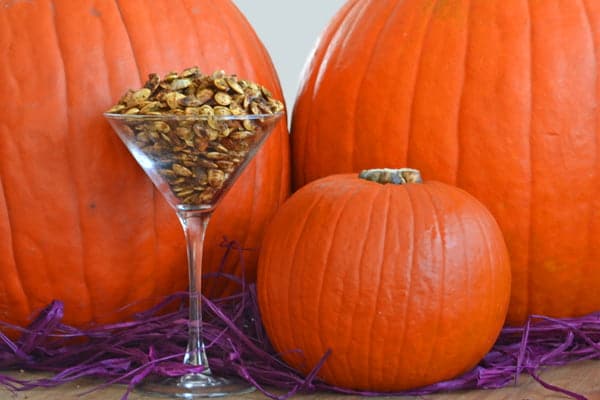 Pesto Parmesan Roasted Pumpkin Seeds in a martini glass in front of pumpkins.