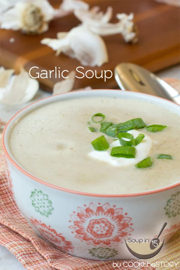 Patterned soup bowl with Garlic Soup topped with sour cream and scallions.