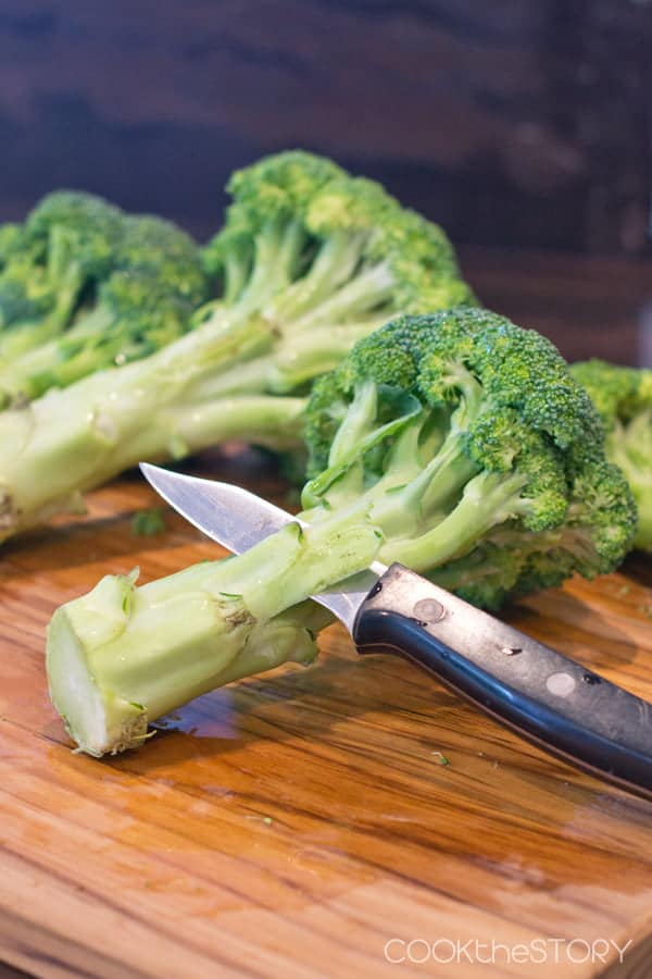 Peeling the broccoli stem with a paring knife.