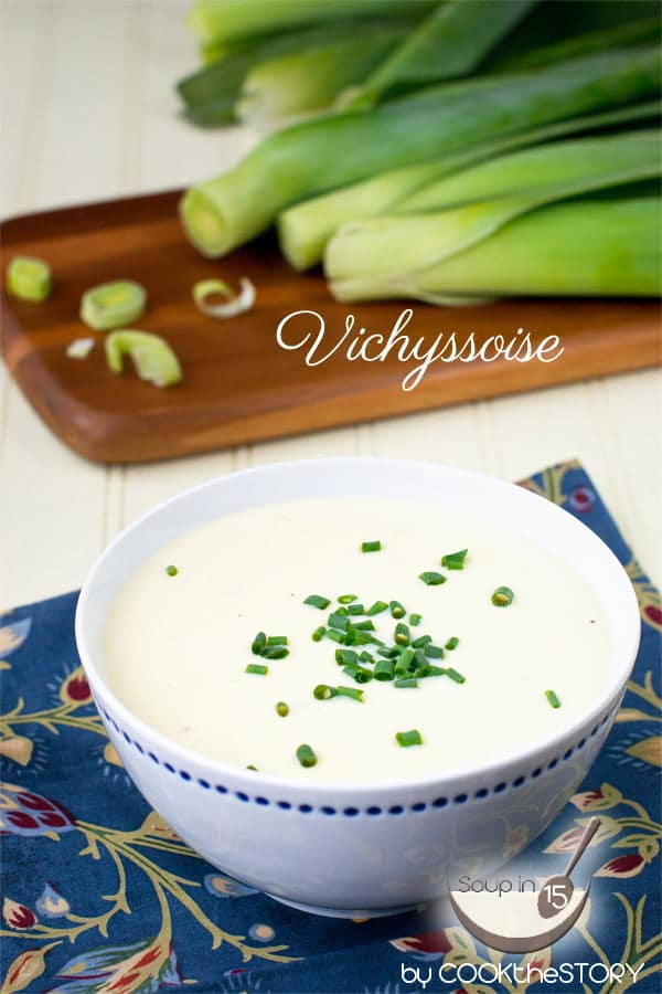 Cold Leek and Potato Soup in a white soup bowl, with cutting board with leeks in background. Text reads Vichyssoise.