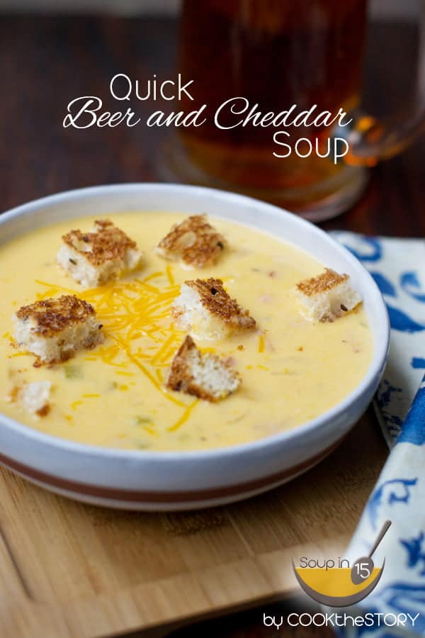 Beer Cheese Soup in a white bowl, topped with croutons and shredded cheese.