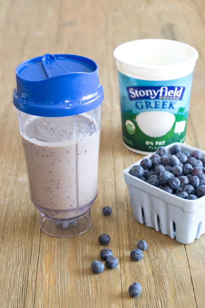 Blueberry Pancake Green Smoothie in a single serve container next to fresh blueberries and Greek yogurt.