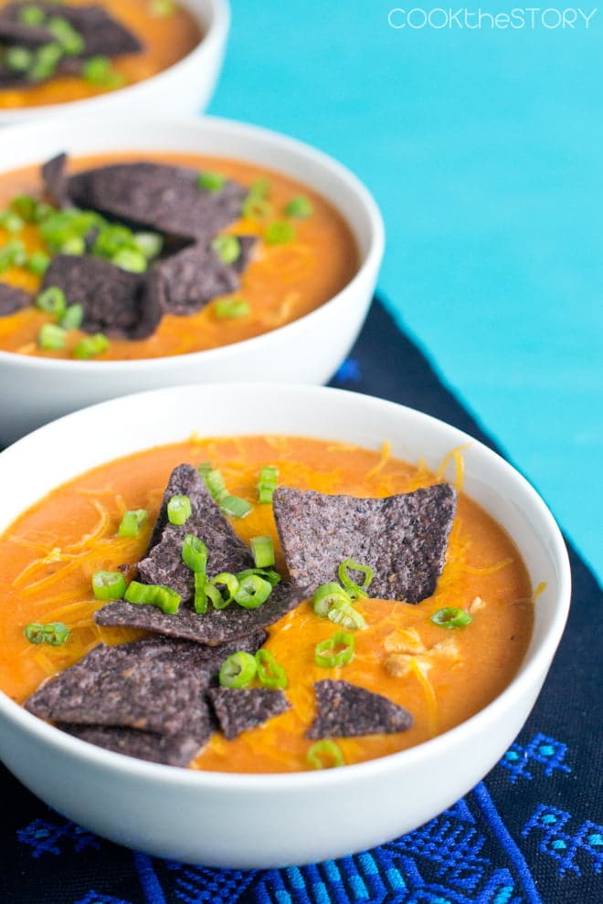 Chicken Enchilada Soup topped with blue corn chips and green onion.