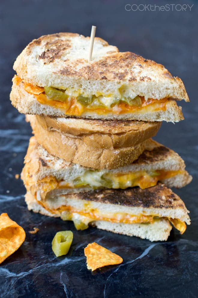 Stack of grill cheese sandwich halves, with jalapenos and doritos inside.