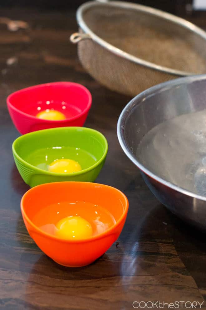 Raw eggs in individual brightly colored bowls.
