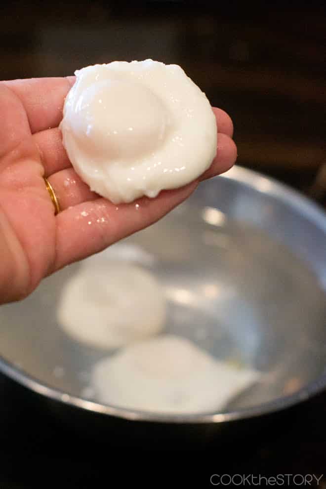 Perfect Poached Egg being held up over ice water bath.