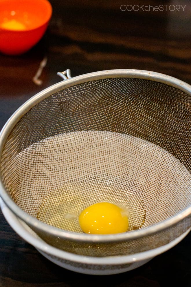 Raw egg in a fine mesh sieve. 