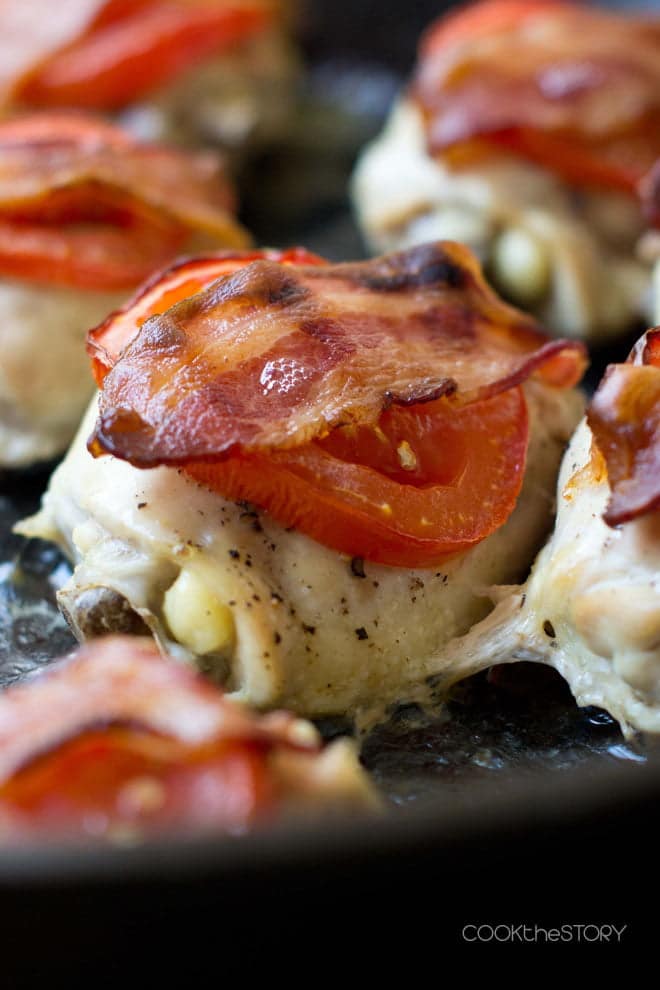 Close up of Chicken BLT, a chicken thigh with a tomato slice and bacon on top.