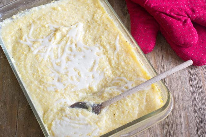 Creamy Polenta topped with cheese in a glass baking dish.