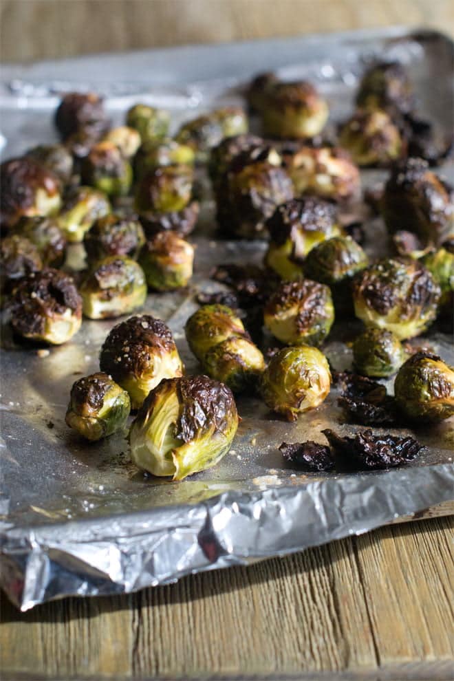 Whole Roasted Brussels Sprouts on an aluminum lined baking sheet.